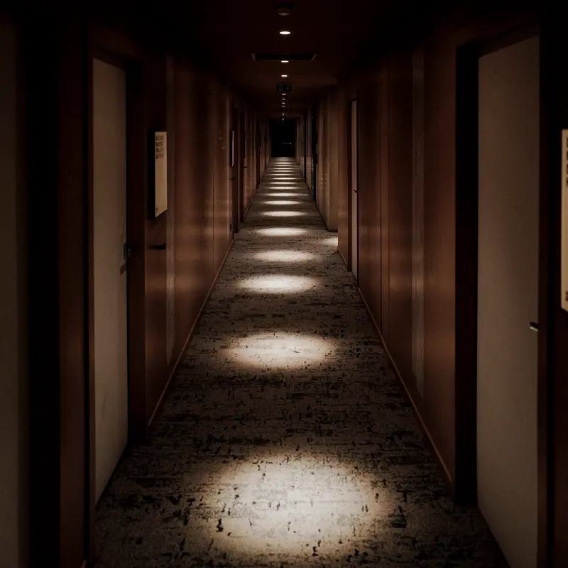 Dark hotel corridor with pools of warm light at each door