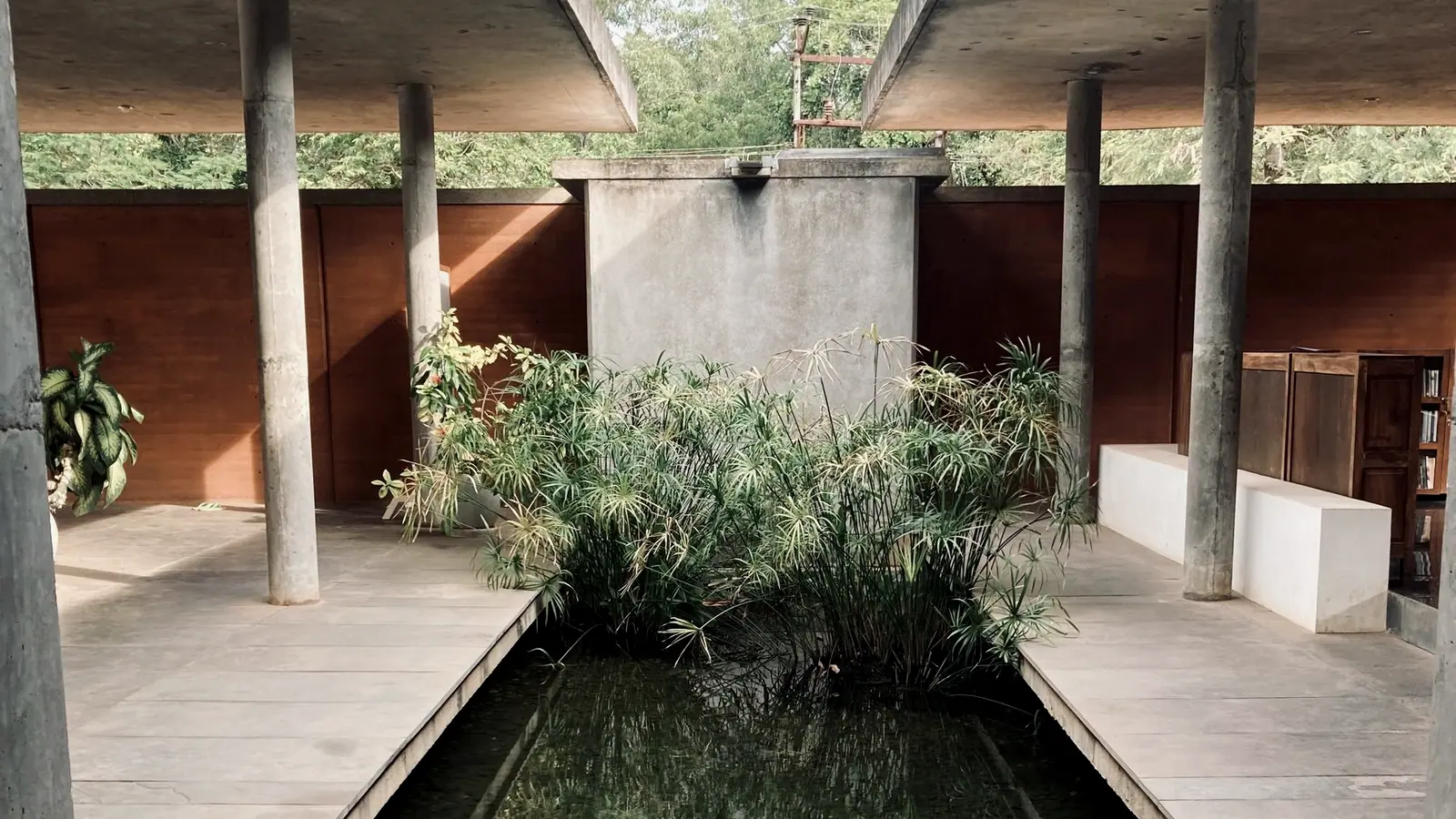 A long water channel running the length of a paved courtyard between ochre walls