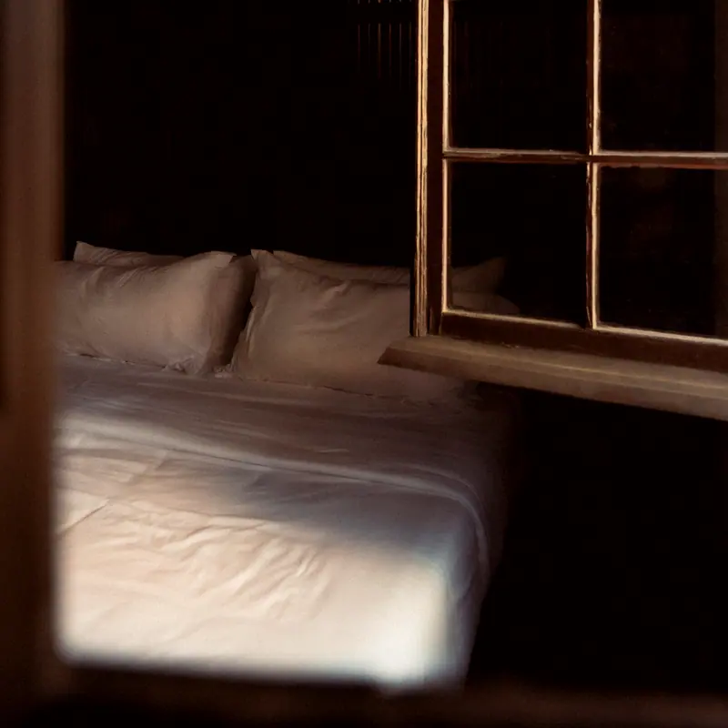 Guest room bed against a tall window at night
