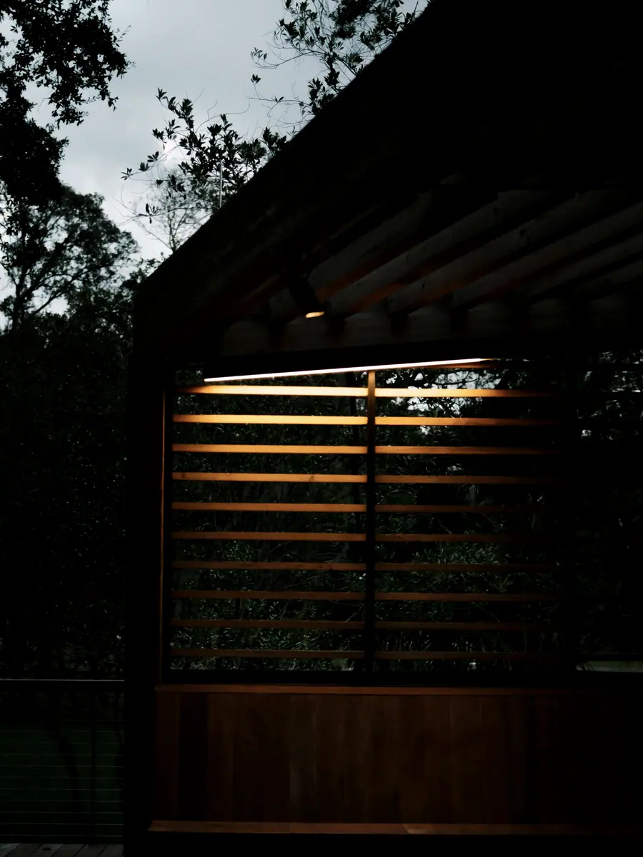Louvred timber shutters half closed, light striping the floor
