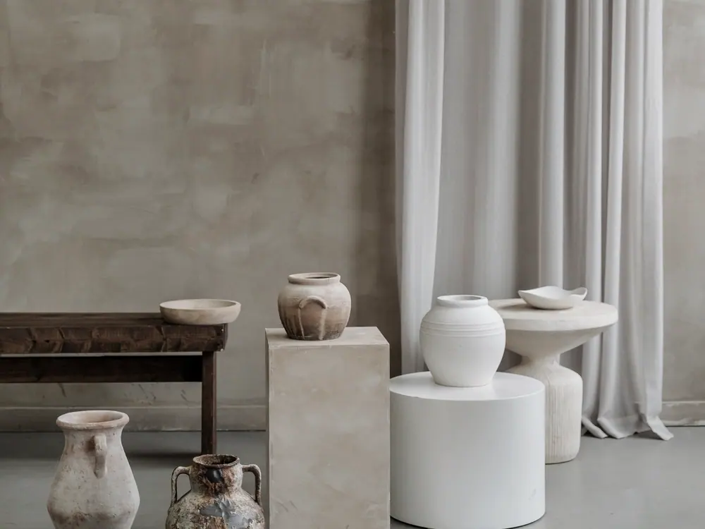 Three vessels standing on a plaster ledge against a bare wall