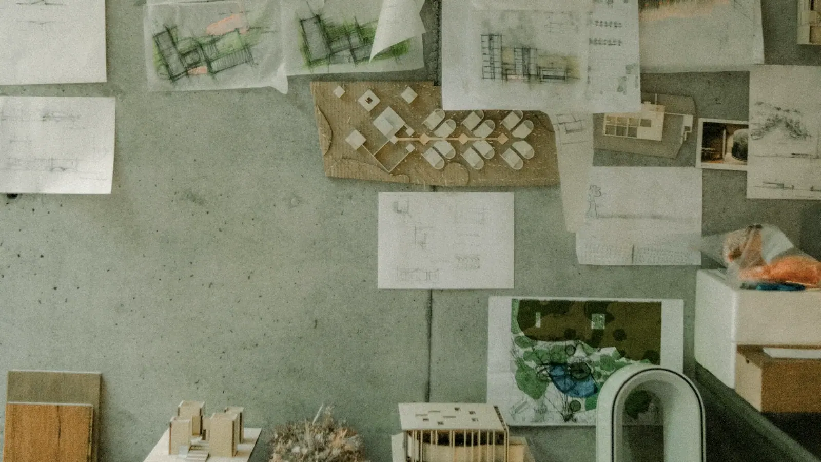 A wall of pinned drawings and material samples in the studio